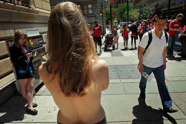 An unidentified male walks past Moira Johnston of suburban Philadelphia as she stands bared breasted along Walnut St. and 18th St in the Rittenhouse section of Philadelphia on June 4, 2013. She says she is making a statement about the sexualization of the female body. ( ALEJANDRO A. ALVAREZ / STAFF PHOTOGRAPHER )