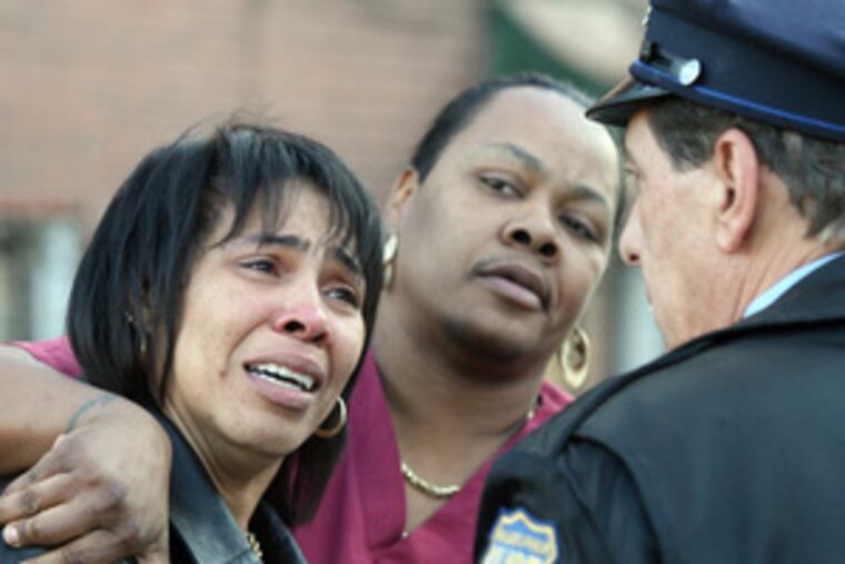 A relative (left) of a shooting victim talks to a Philadelphia cop Sunday on Pentridge Street near 58th, in Southwest Philadelphia. Police said Jovonne Stelly, 28, a mother of four, was an innocent bystander killed in the incident.