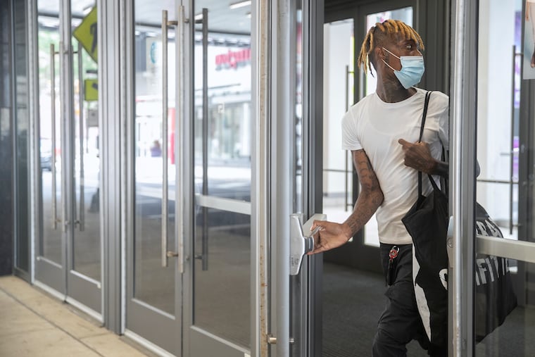 A masked pedestrian exits the Fashion District in Center City on Thursday. The city announced that day officials "strongly recommend" masks indoors due to an increase in COVID-19 cases around the country among the unvaccinated.