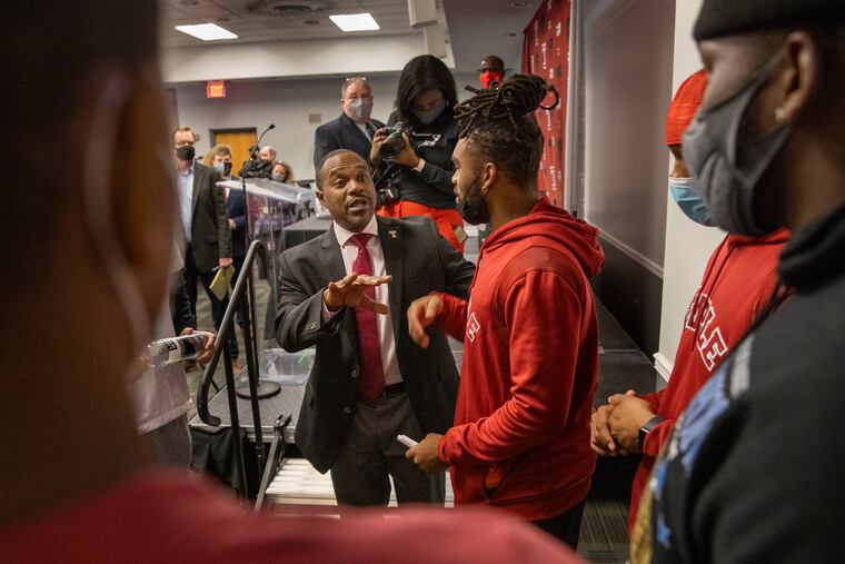 Stan Drayton with football player Cameron Ruiz, surrounded by other players after press conference.