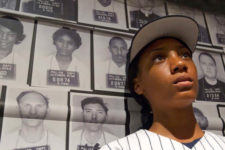 Mo'ne Davis leans against a collection of mug shots of Freedom Riders as she listens to Freedom Rider Hank Thomas talk about his experiences at the Center for Civil and Human Rights in Atlanta.