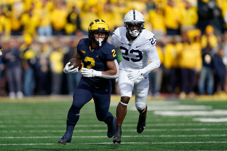 Michigan running back Blake Corum runs with the ball as Penn State linebacker Curtis Jacobs pursues him on Saturday.