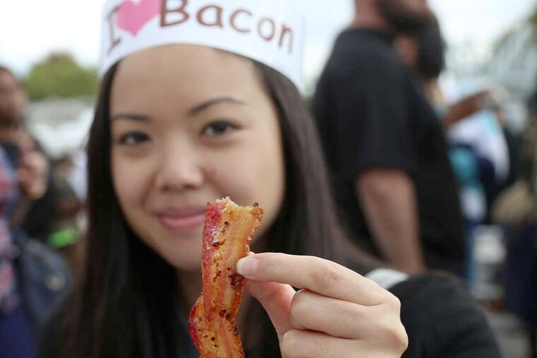 Parim Sukosi holds up maple-candied bacon at the Pennsylvania Bacon Festival at Xfinity Live!