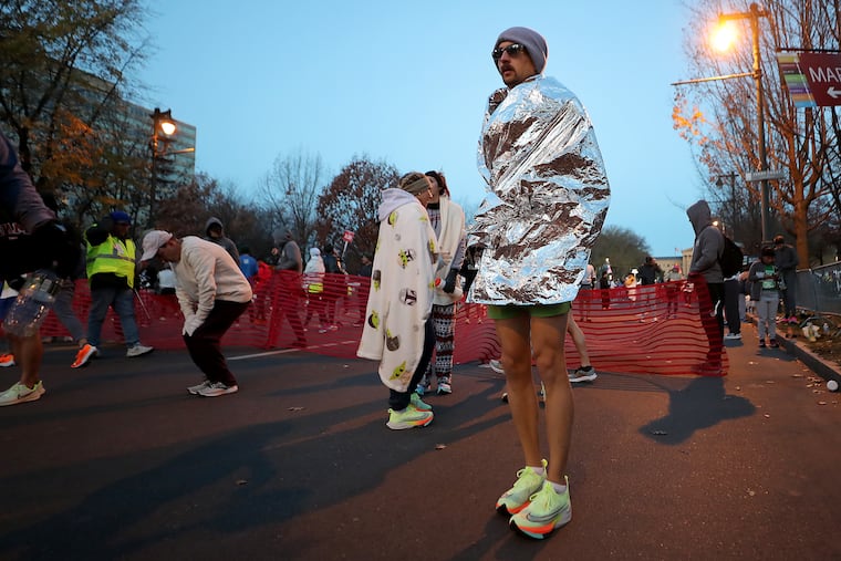 Peter Wall, of Binghamton, N.Y., tries to stay warm before the start of the Philadelphia Marathon on Sunday.