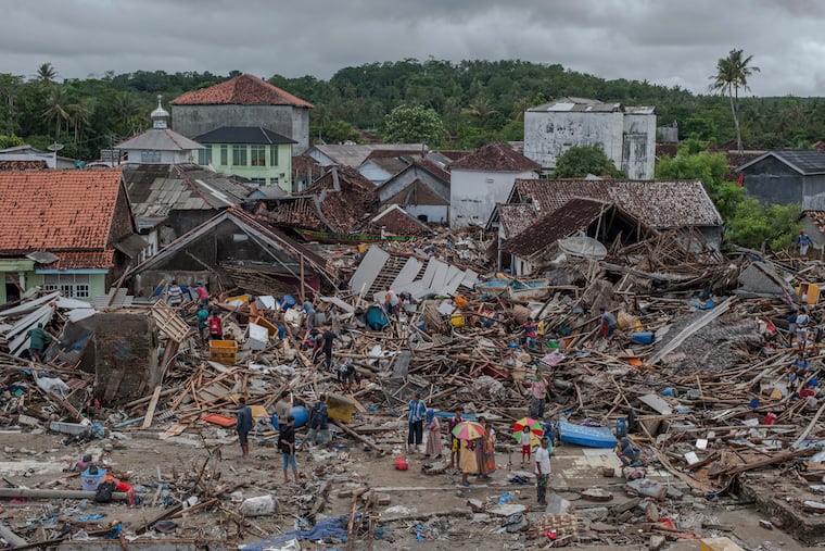In this Monday, Dec. 24, 2018, photo, people inspect the damaged at a tsunami-ravaged village in Sumur, Indonesia. The tsunami that hit the coasts of Indonesian islands along the Sunda Strait was not big but it was destructive. The waves smashed onto beaches in the darkness Saturday night without warning, ripping houses and hotels from their foundations in seconds and sweeping terrified concertgoers into the sea. (AP Photo/Fauzy Chaniago)