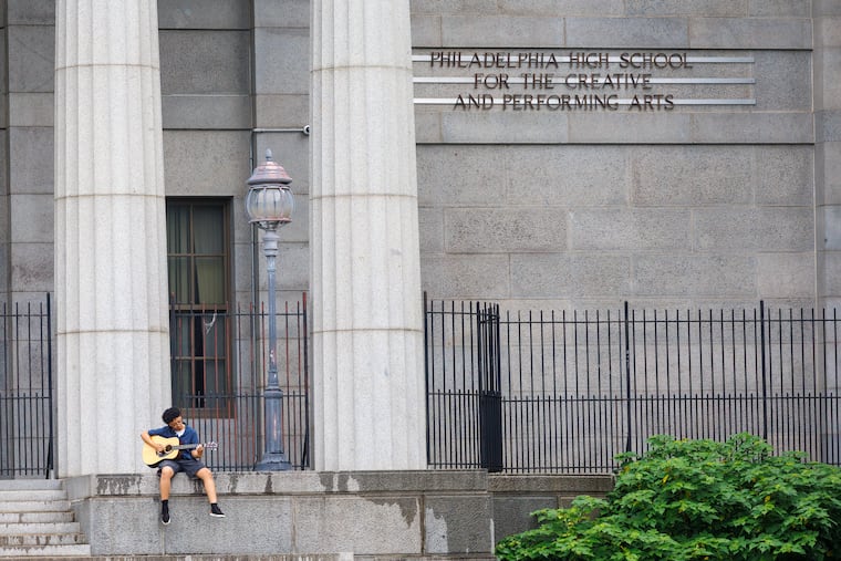 A student strums his guitar outside the Philadelphia High School for Creative and Performing Arts. The school has been beset by turmoil, and parents, students and teachers say that some students were given fake grades for a class that received no instruction.