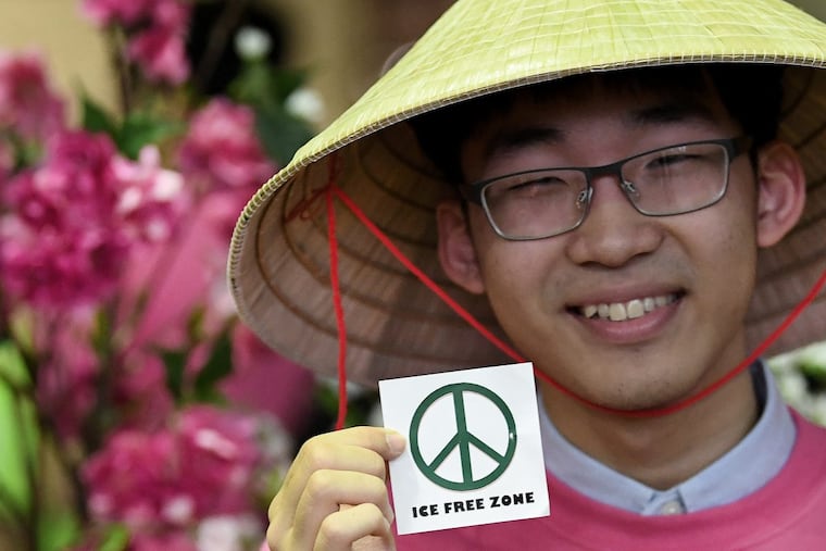 Nguyen Dang of Philadelphia shows a sticker in support of anti-deportation activism during the Tet celebration Furness High School in South Philadelphia on Sunday.