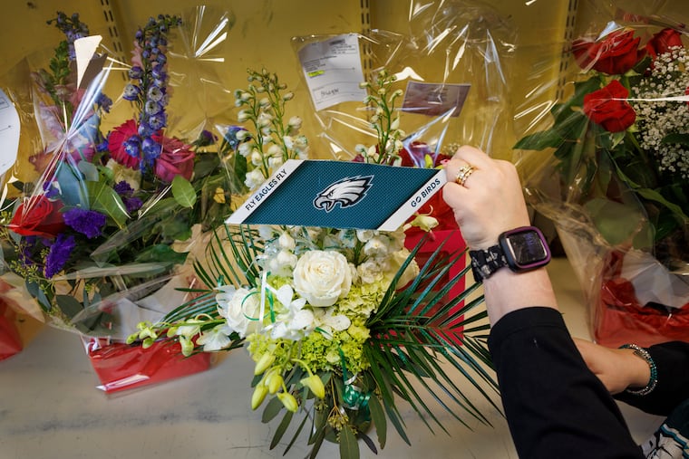 At Ten Pennies Florist, manager Nicole Miles puts the finishing touches on an Eagles-themed arrangement on Wednesday. The South Broad Street flower shop made the difficult decision to close on Friday, Valentine's Day, due to the holiday conflicting with the Eagles Super Bowl parade.