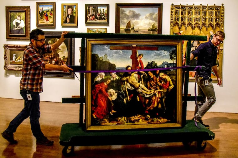Installation technicians Hiro Sakaguchi (left) and Noah Yoder wheel Joos van Cleve’s 1518 painting “Descent from the Cross” through the exhibition space at the Philadelphia Museum of Art.