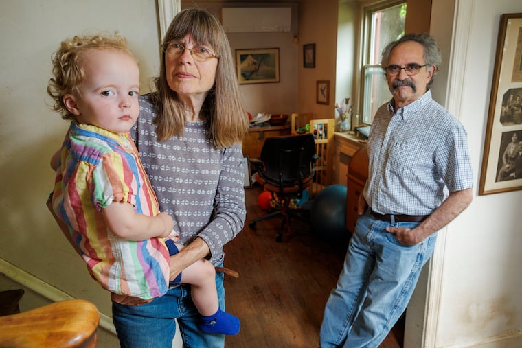 Pamela Albright, a retired nurse who lives in Melrose Park, opted to cancel her care at Temple University Hospital after being asked about her citizenship. This photograph was taken at her home on Tuesday, May 13, 2025. She is holding grandson Avery Libros-Applefield, 2, and at right is her husband, Randy Libros.