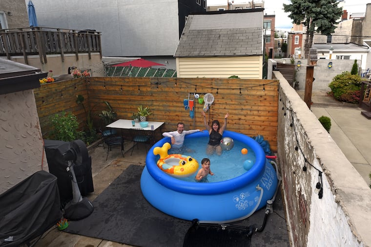 Resigned to staying put at their Fishtown home this summer, Matthew Fisher and Bobbie Ann Tilkens-Fisher installed a blow-up pool in their rowhouse yard. Here, they cool off with their 3-year-old son, Milo.