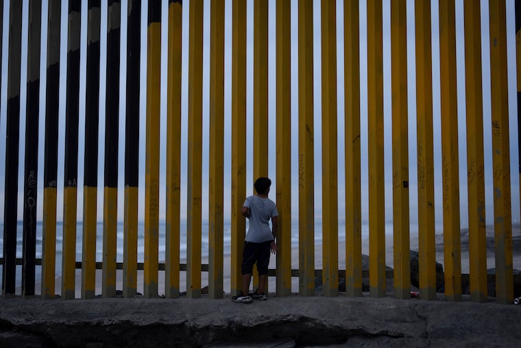 A boy looks through a border wall separating Mexico from the United States in November 2024.