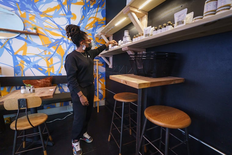 Taahirah Stith arranges a display of her Beans and Brains Dope Botanicals, a company she runs with her sister Nakia, in a new section of the Bower Cafe that will function as a store, in Washington Square West. Stith is selling cut herbs, teas, liquids, syrups, tinctures and powders, all natural products for better health and well being, in a new section of the cafe.