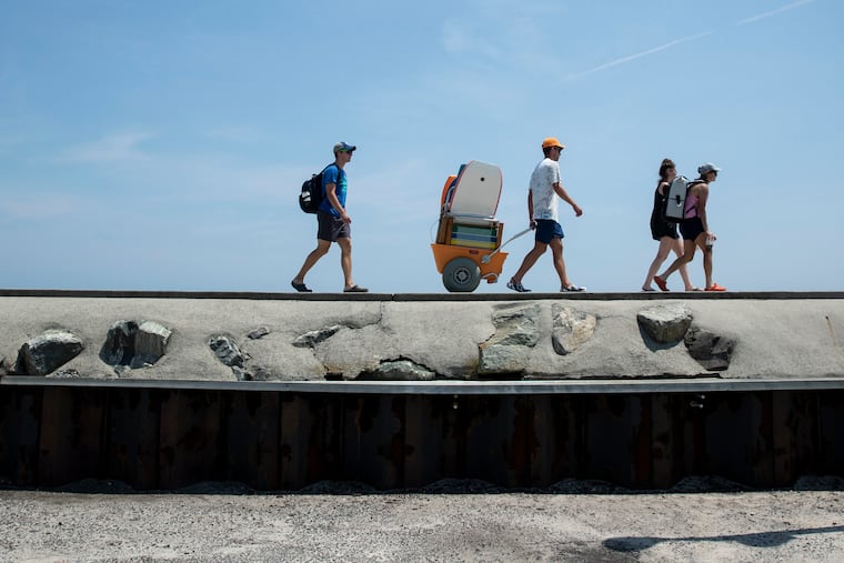 File: Beachgoers walk along the North Wildwood seawall, which the towns plans to extended to 7th Street.
