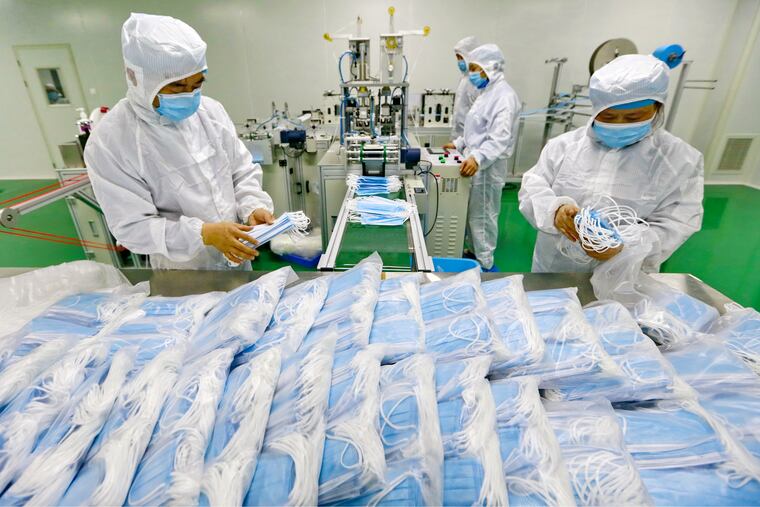 In this Feb. 7, 2020, photo, workers pack surgical masks at a factory in Suining city in southwest China's Sichuan province.