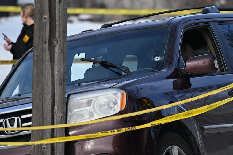 A bullet hole is seen in the windshield as law enforcement officers work at the scene of a shooting involving an ICE agent Wednesday in Minneapolis.