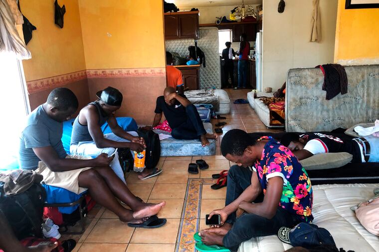 In this July 28, 2019, photo, Cameroonians wait in a rented apartment in Tijuana, Mexico, until their names are called to claim asylum in the U.S. The Cameroonian men who share 10 mattresses on the floor of a third-floor apartment above a barber shop walk every morning to the busiest U.S. border crossing with Mexico, hoping against all odds that it will be their lucky day to claim asylum. Their unlikely bet is that a sympathetic Mexican official will somehow find a spot for them. (AP Photo/Elliot Spagat)