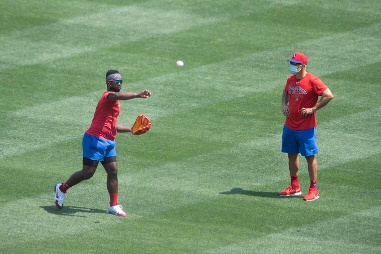 Phillies manager Joe Girardi, right, watches as left fielder Andrew McCutchen makes a throw during a training-camp workout at Citizens Bank Park.