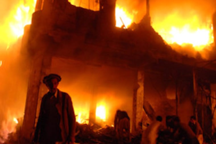 Pakistanis try to extinguish a fire after a blast in Peshawar yesterday. One resident said that rescues were complicated by power failures and that gas pipes ruptured.