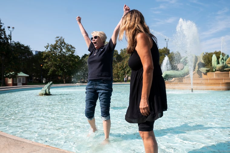 Jackie Kelly, a Hallahan Catholic Girls’ High School alumni from the Class of 1982, cheers next to Anna Brown, Class of 1976, after dipping into the Swann Memorial Fountain at Logan Square in Philadelphia on Saturday, Oct. 12, 2024. Alumnae from the school reunited to honor the legacy and tradition of dipping into the fountain after the last day of school.