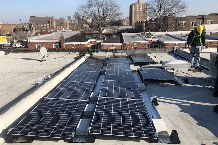 An employee of Solar States looks over a recent photovoltaic installation on a West Philadelphia rooftop. Owners of some solar systems installed this year have been unable to connect their systems to the power grid because of coronavirus restrictions on Peco workers, shutting the owners out of a city solar rebate program.