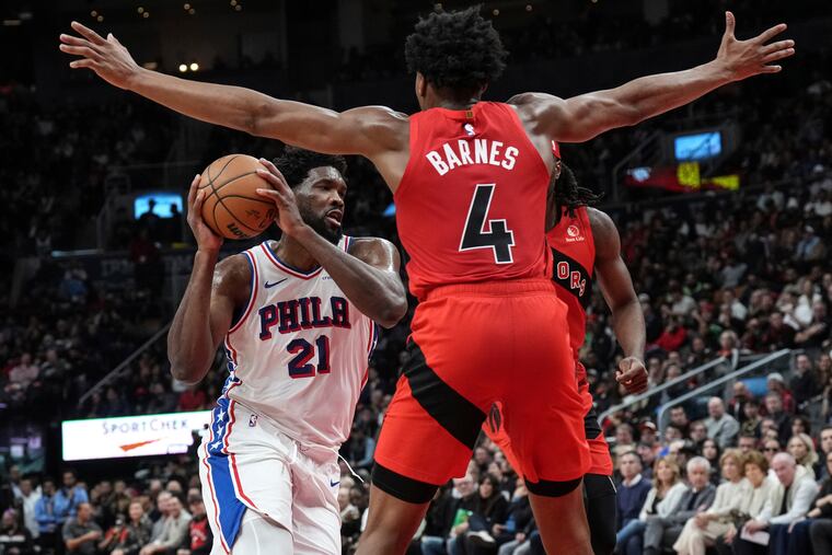 Sixers center Joel Embiid drives between Toronto's Scottie Barnes and Precious Achiuwa during the second half Saturday.