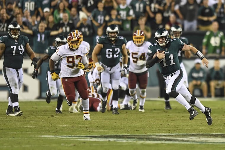 The Eagles quarterback Carson Wentz escapes the scrum behind him — which was a certain sack — and runs 17 yards for a first down during the game against the Washington Redskins at Lincoln Financial Field October 23, 2017. Eagles beat Washington 34-24.