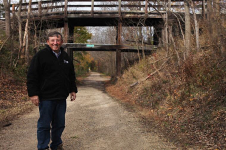Theodore F. Poatsy Jr., chairman of the Upper Salford supervisors, stands beneath the Reading Railroad bridge that the township is auctioning off. (Juliette Lynch / Staff Photographer)