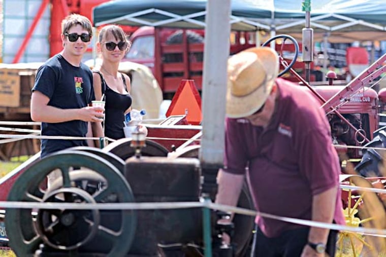 Zack Sabo, 25, of Burlington Township and Pattianne Kritz, 27, of Willingboro watch Larry Cauffman, 83, of Masonville demonstate his 1925 Fairbanks Morris 3 horsepower, single cylinder kerosine engine during the first full day of Burlington County Farm Fair July 16, 2014. Cauffman is a collector of antique farm machinery. Sabo grew up on a farm, so misses the equipment. "I wish I still had one," he says, referring to a tractor. "That's how I learned to drive," he added. Kritz had no comment. ( TOM GRALISH / Staff Photographer )
