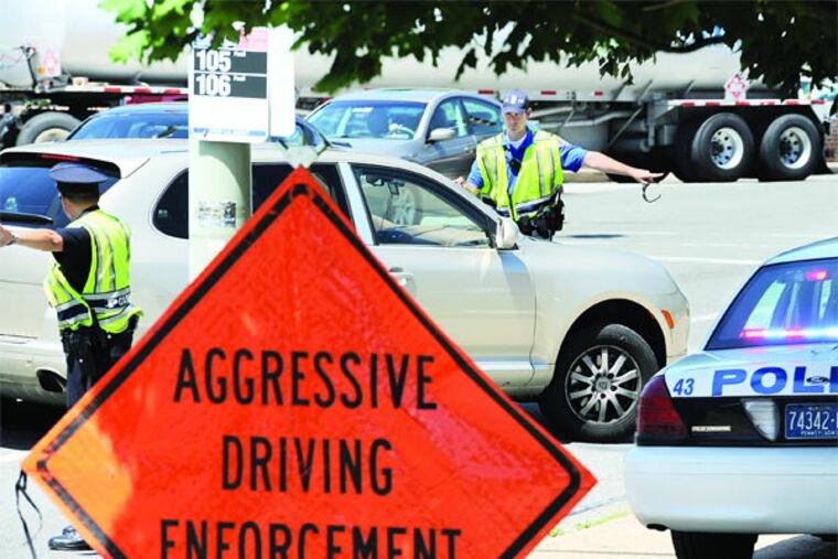 Lower Merion police officers M.T. Miller (left) and Joseph Hunsicker, wade into traffic on Lancaster Ave. in Bryn Mawr July 15, 2013 to pull over a speeder as part of a Pennsylvania initiative known as "Heat on 30" which targets aggressive driving behaviors such as speeding, tailgating and running red lights on Route 30 throughout the state. The initiative will run through Juy 19, 2013. ( CLEM MURRAY / Staff Photographer )