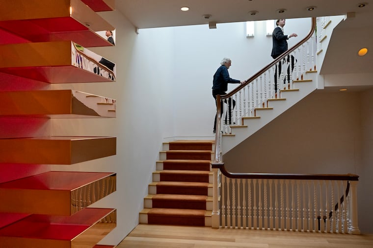 “Untitled” (detail) by Donald Judd (1928-1994) copper and red fluorescent Plexiglas, in the second floor family room of the Delancey Street home of Hank McNeil, Jr., March, 12, 2026. Christie’s is offering McNeil’s collection, known to be the best minimalism collection ever compiled. It includes a who’s who of the category, including Flavin, LeWitt, and the best Donald Judd stack ever offered privately. Walking up the staircase - the only original part of the house that was saved and restored - are Jake Quinn, a real estate and collection manager, and longtime McNeil friend and caretaker of the home; and William Featherby (right), junior specialist, post-war and contemporary art, at Christie’s.
