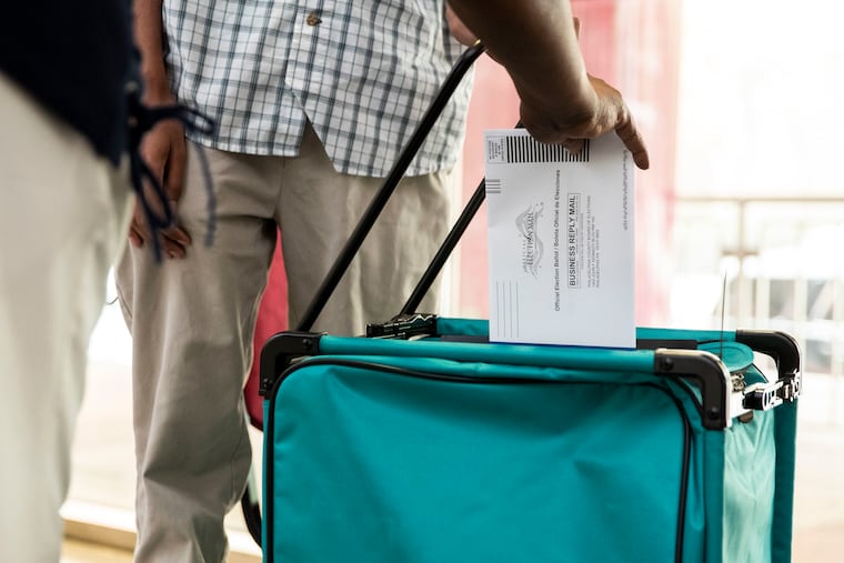 A mail ballot is cast during a news conference at a satellite election office at the Liacouras Center last month.