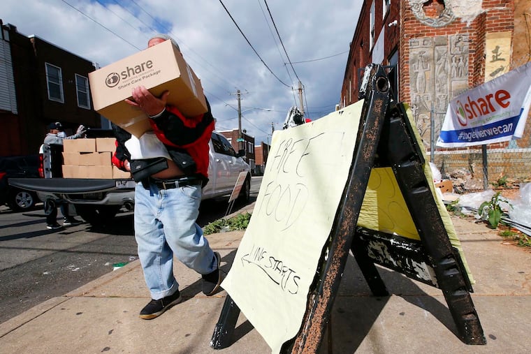 A resident carries his box of food from the Share Food Program distributed at the Young Chances Foundation in the Point Breeze neighborhood of Philadelphia in the spring of 2021. After over 30 years of the Share Food Program managing the city’s The Emergency Food Program (TEFAP) without a problem, the city’s Office of Homeless Services (OHS) was recently given the responsibility. (Yong Kim/Philadelphia Inquirer/TNS)