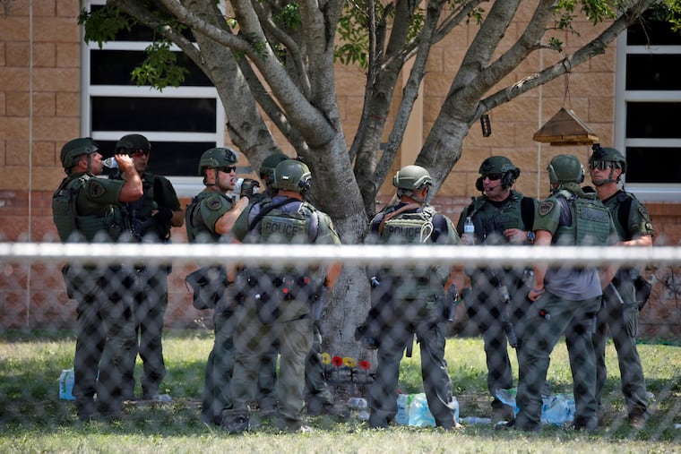 Law enforcement personnel stand outside Robb Elementary School following a shooting, May 24, 2022, in Uvalde, Texas. When the gunman arrived at the school, he hopped its fence and easily entered through an unlocked back door, police said. He holed himself up in a fourth-grade classroom where he killed the children and teachers.