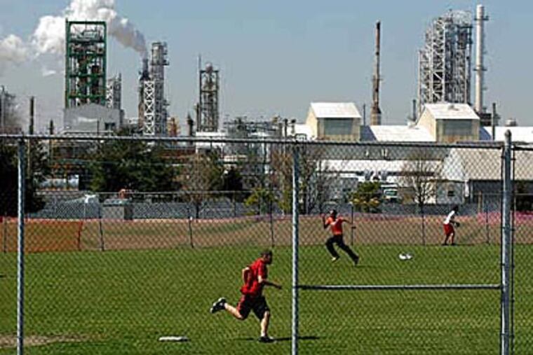 Students at Paulsboro High School play kickball next to an oil refinery. PBF Energy’s refinery plans to lay off 250 employees and halt fuel production as a result of low demand.