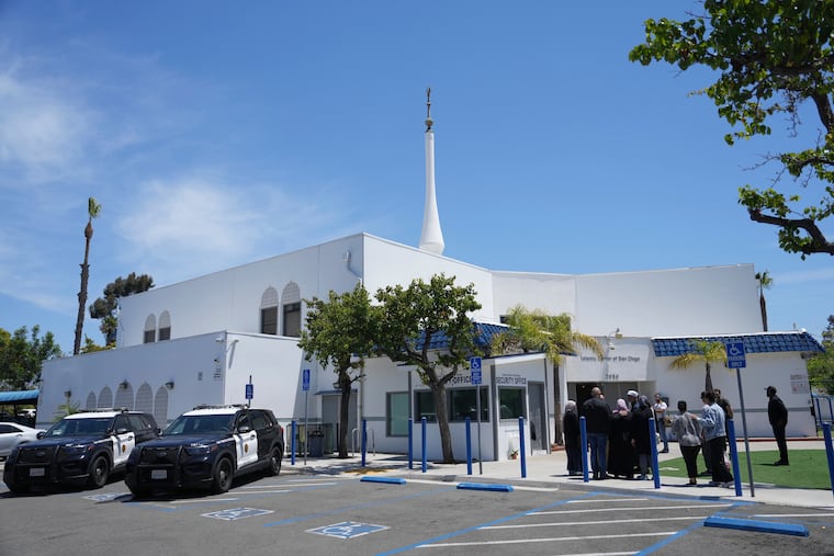 People gather as police vehicles are parked outside of the Islamic Center of San Diego, the day after a shooting, May 19, 2026, in San Diego.