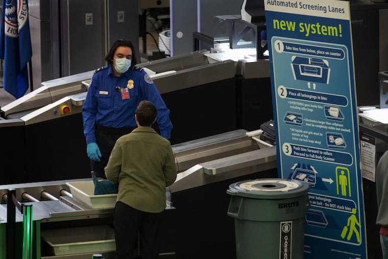 A TSA worker wears a mask while helping travelers get through Security Checkpoint 1 at Seattle-Tacoma International Airport.