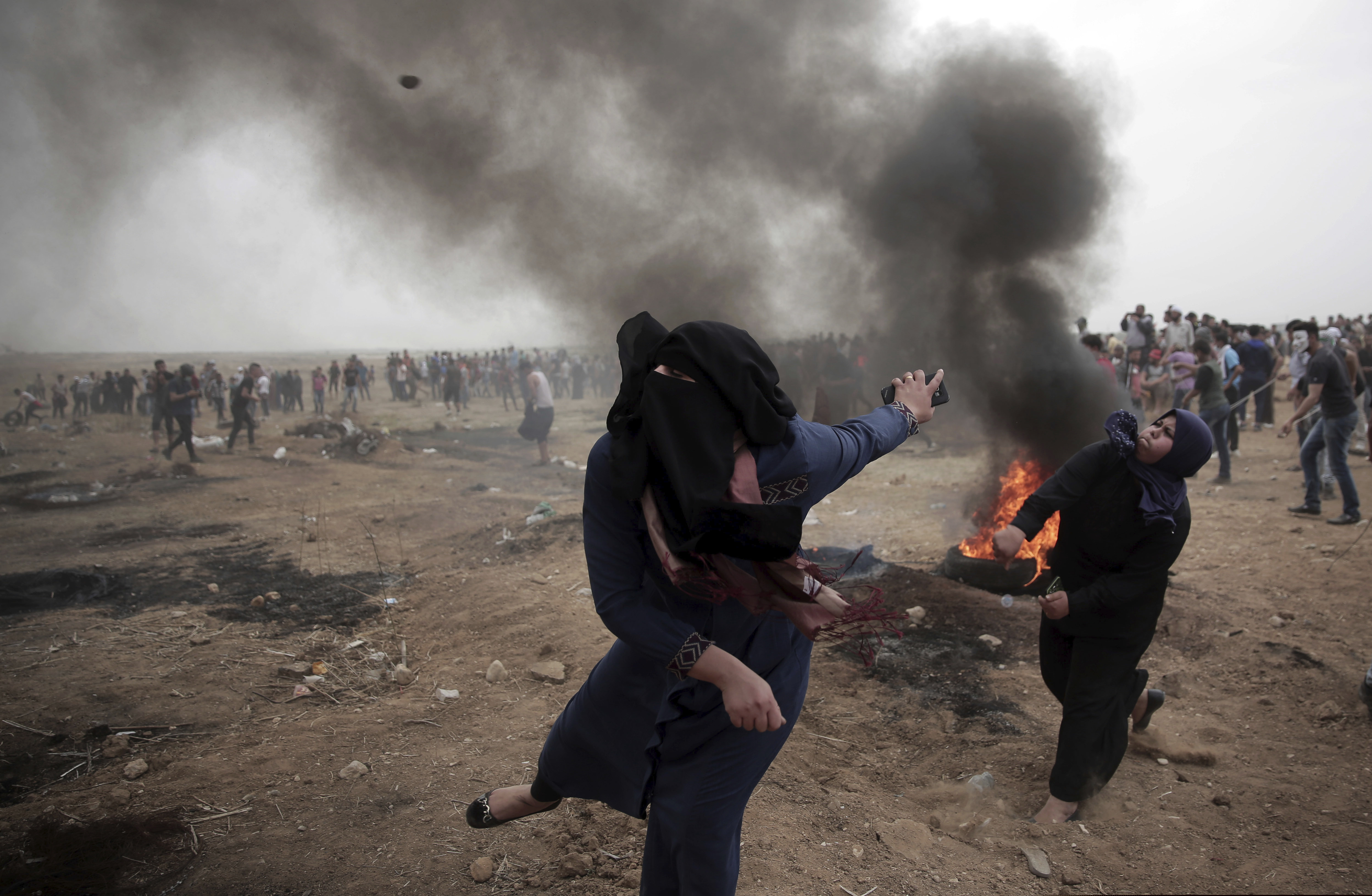Palestinian women hurl stones at Israeli troops during a protest at the Gaza Strip's border with Israel on May 4, 2018. (AP Photo/ Khalil Hamra)