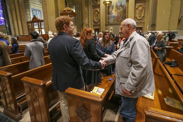 The congregation at the morning mass at St. Peter and Paul on October 28, 2018, shake hands as they offer each other the sign of peace the day after the synagogue shooting in Pittsburgh.