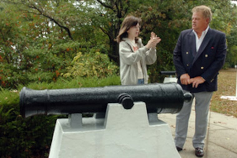 Standing by a cannon from the HMS Augusta are Mark English of Haddonfield and Megan Giordano, curator at the Red Bank Battlefield. English plans to auction off a carved staircase pedestal from the Revolutionary War ship to establish college scholarship funds.
