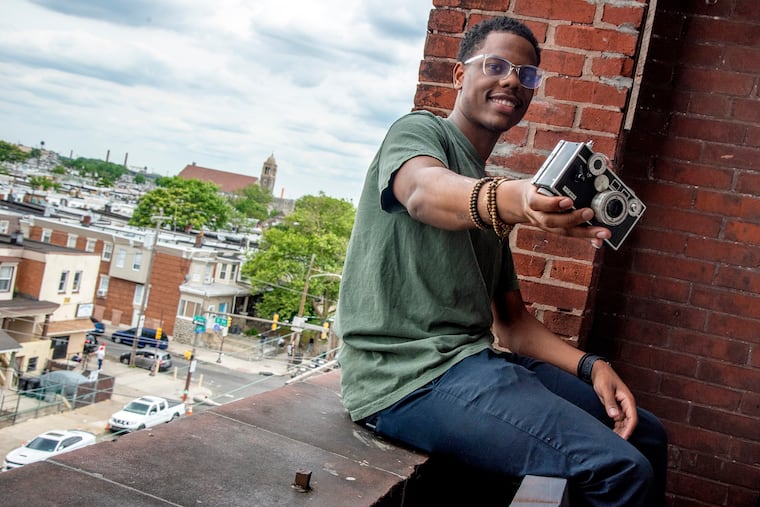 CJ Wolfe poses with a camera once owned by his great-grandfather, Oliver Barton, on the balcony at his Immortal Vision Studio in Kensington.