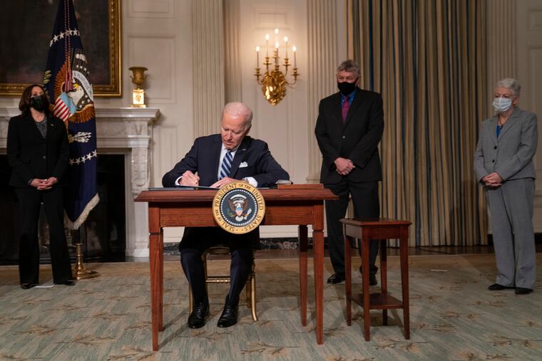 President Joe Biden signs a series of executive orders on climate change, in the State Dining Room of the White House on Jan. 27, 2021. From left, Vice President Kamala Harris, Biden, White House science adviser Dr. Eric Lander, and National Climate Adviser Gina McCarthy.