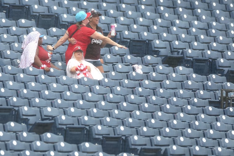 Fans dance in the rain during a rain delay before a Phillies game in 2025.