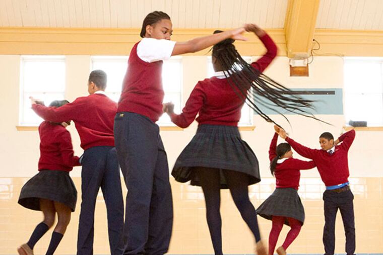 Eighth graders Issac Jones and Sinyah Patrick (center) dance at Dancing with the Students practice in the gymnasium of Drexel Neumann Academy, in Chester on April 2, 2014. ( DAVID M WARREN / Staff Photographer )