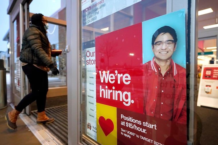 A passer-by walks past an employment hiring sign while entering a Target store in Westwood, Mass.
