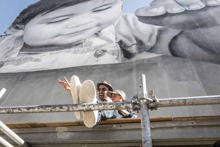 JR (left) and Kikito on scaffolding in Tecate, Calif., along the border with Mexico, in a scene from the documentary "Paper & Glue."