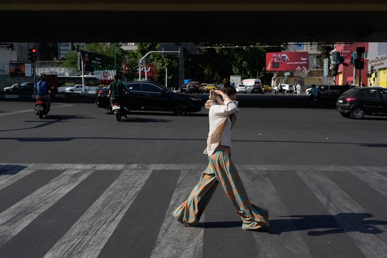 A woman adjusts her headscarf as she crosses an intersection in northern Tehran, Wednesday, June 10, 2026.