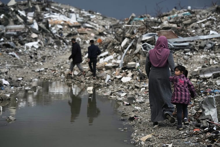 Palestinians walk through rubble amid stormy weather in Gaza City Thursday.