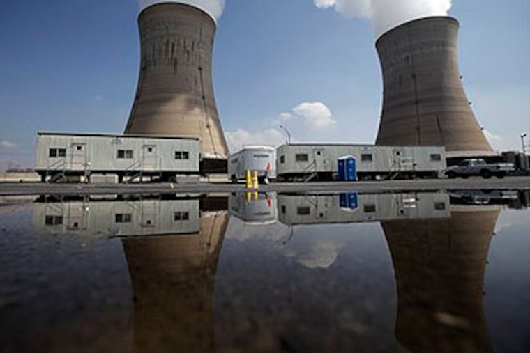 The cooling towers of Three Mile Island's Unit 1 reactor are reflected in a puddle in a parking lot in Middletown, Pa. (AP Photo / Carolyn Kaster)