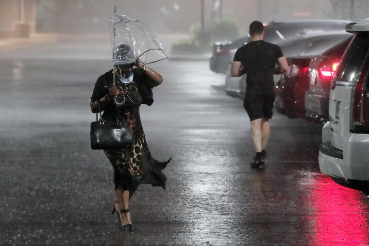 Diane Hall of Lindenwold navigates thru the pouring rain in a Bellmawr parking last month. More showers are expected this week.